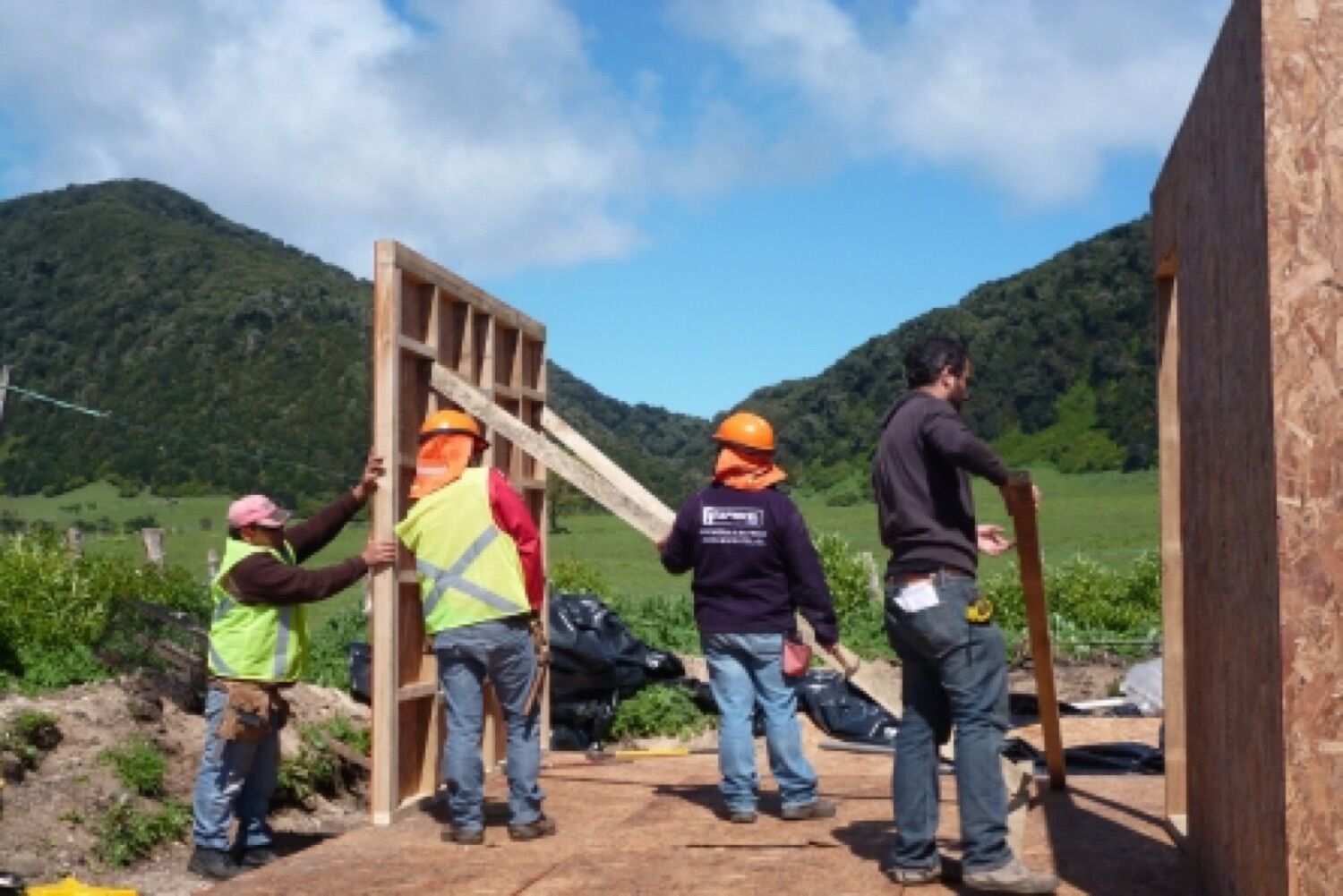 Comunidad levantando la estructura de una vivienda junto al equipo